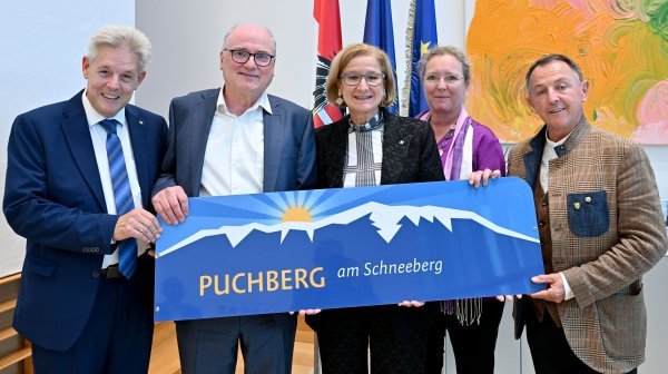 fünf Personen stehen nebeneinander und halten ein Schild in die Kamera